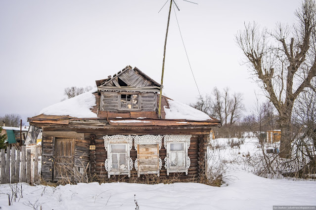 Разрушающийся деревянный дом с белыми наличниками