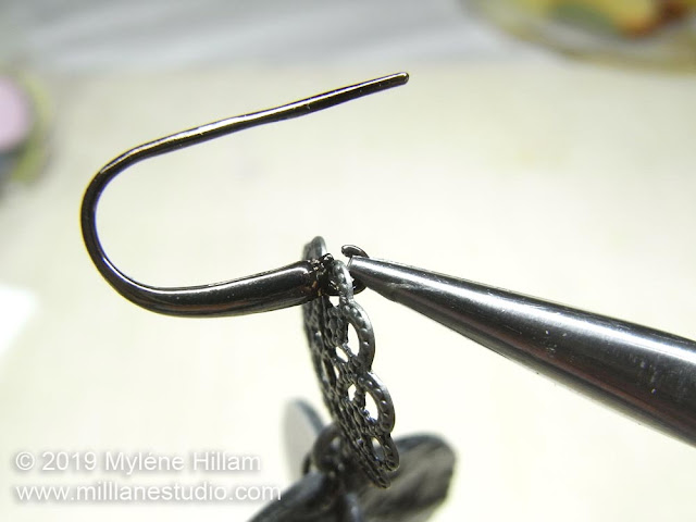 Using pliers to close the loop on the earring wire.