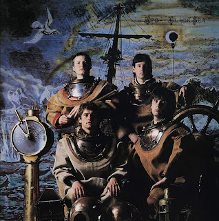 Bandmembers dressed in old fashioned diving gear beside a ships telegraph