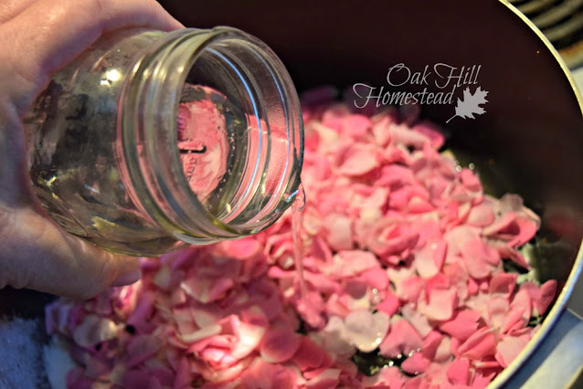 Pouring a jar of water into the pan of rose petals.