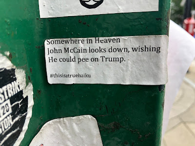 True Haiku sticker on bus stop, water damaged, reads "Somewhere in Heaven/John McCain looks down, wishing/He could pee on Trump. #thisisatruehaiku"