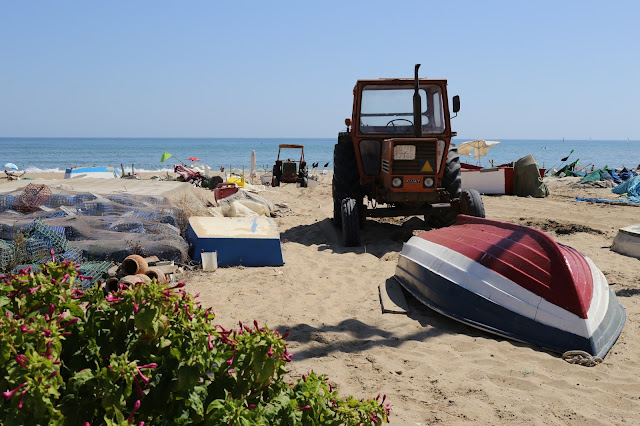 Máquinas, herramientas y útiles de pescadores sobre la arena de la playa con las azules aguas del océano atlántico al fondo.