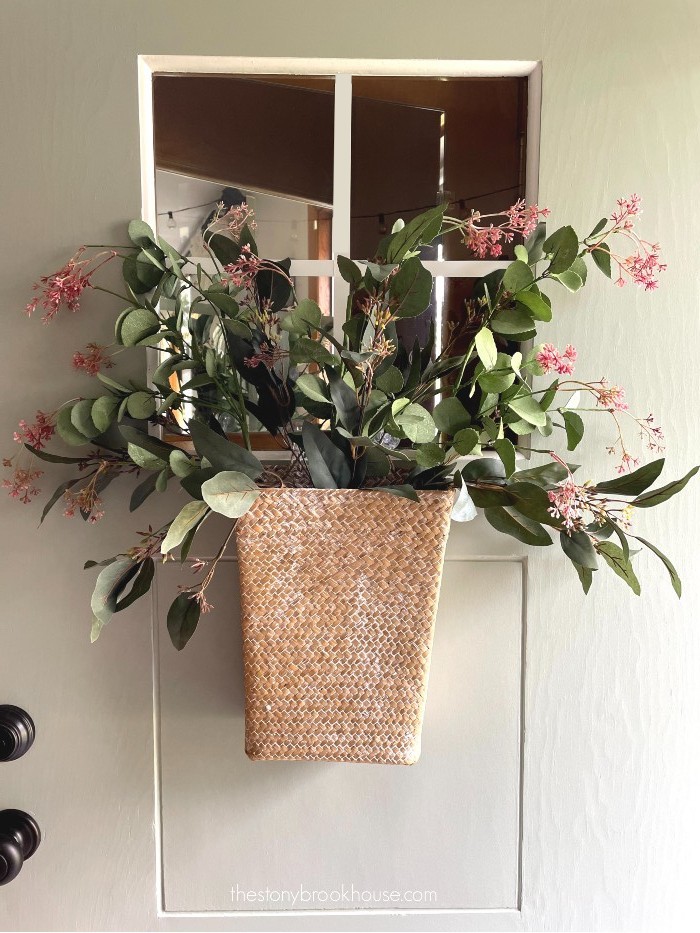 Adding greenery with flowers to front door basket