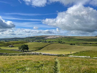 A stone wall and stone farm house in the middle of fields.