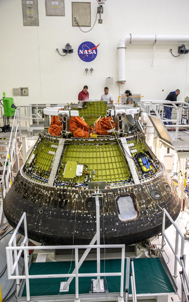 Part of the thermal protection system is removed from the Artemis 1 capsule, as technicians prepare to take out equipment that will be reused on the Orion spacecraft for Artemis 2.