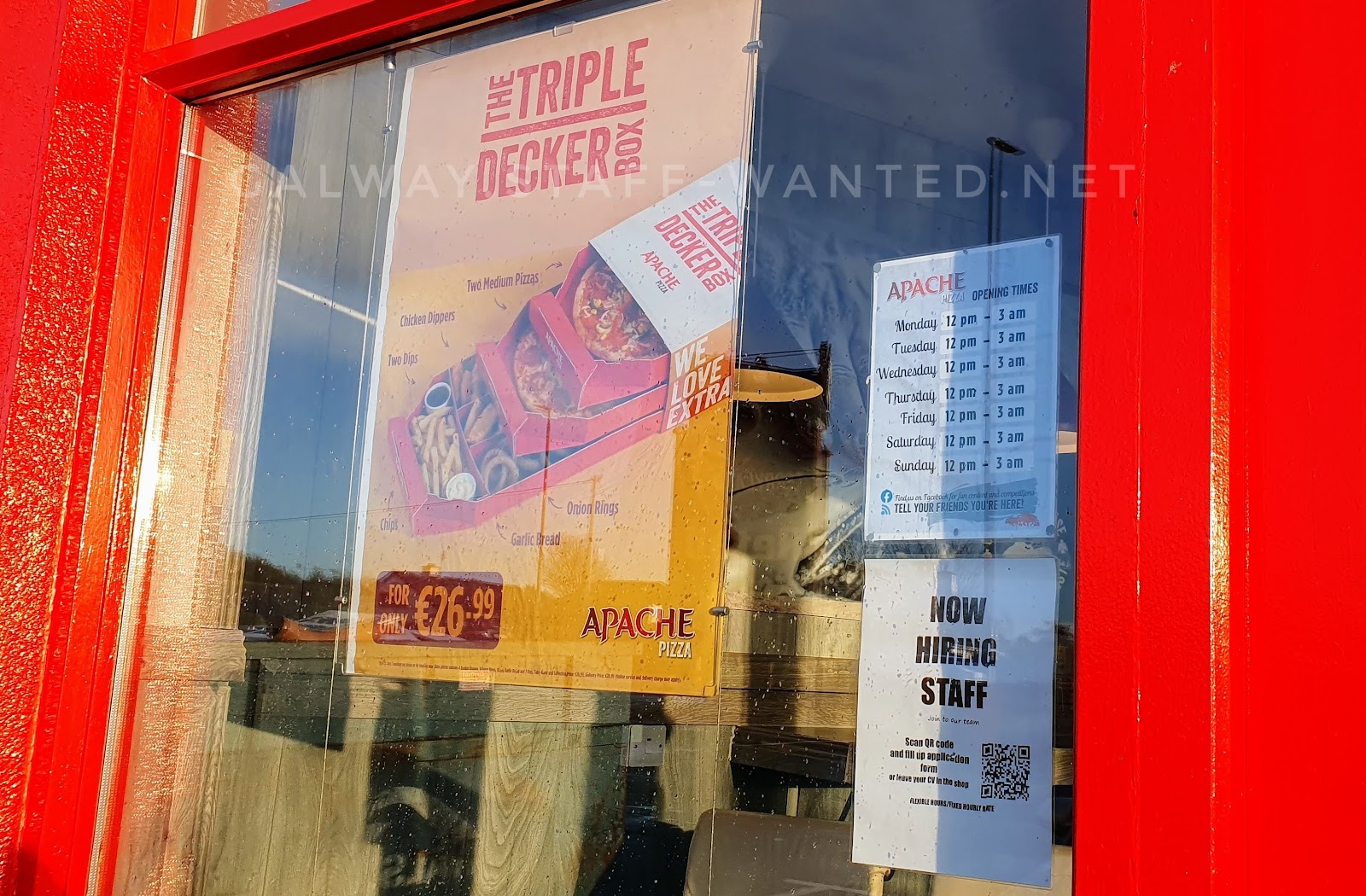 Apache Terryland front window with staff wanted sign, and a poster showing their triple-decker-pizza- box