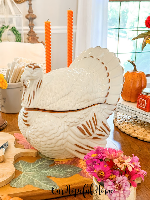 fall dining table with ceramic turkey and orange taper candles in brass candleholders