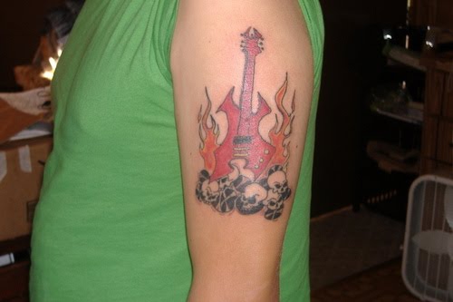 Guitar Tattoo Design with skull and fire on guys upper arm