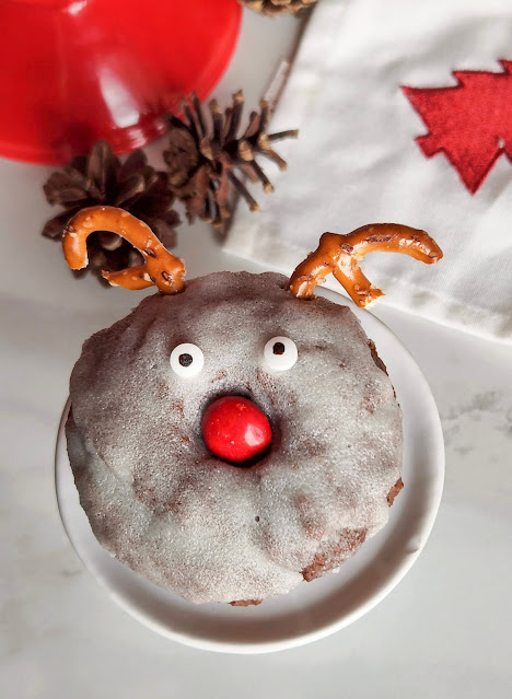 donut on a round white plate with pinecones in the background.