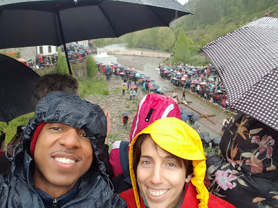 Lots of people standing in the rain watching almadias go down the river