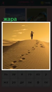  по пустыне в жару двигается человек, оставляя свои следы на песке