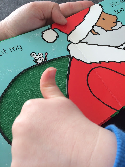 A children's book with fabric insert on the page, with a childs hand playing with it