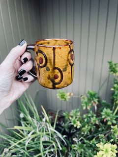 A hand holding a vintage mug