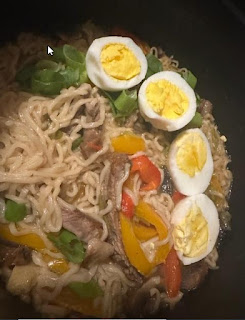 Bowl of ramen with scallions, vegetables, and eggs.