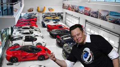 ID: Elon Musk looks smug in front of a fleet of fancy shmancy red and white electric vehicles.