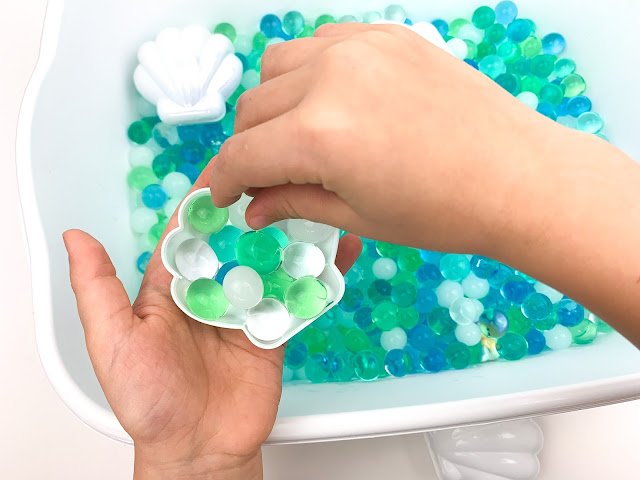 water beads inside a sea shell held in a child's hand.