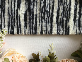 Zebra-striped knitted tube surrounded by peach flowers