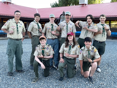 A group of Boy Scouts in uniform placing emphasis on new Philmont patches on their uniforms