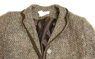 Photo of the top half of black, white, and aquamarine blue tweed blazer featuring a aquamarine blue and silver button.