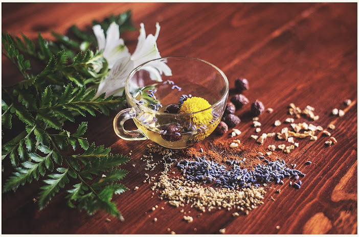 A wooden table with various natural remedies, including herbs, spices, and brewed tea.