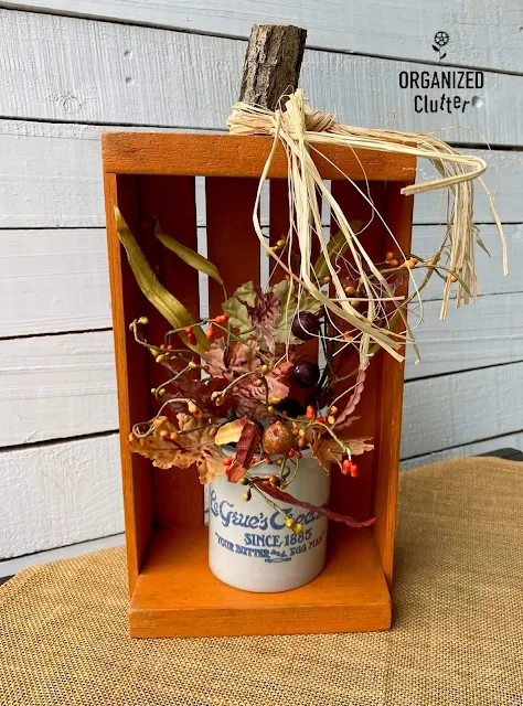 Photo of a crate pumpkin holding fall foliage