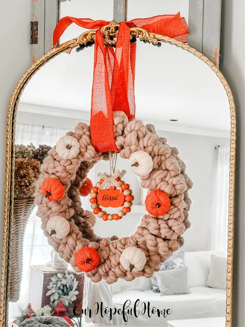 chunky knit fall wreath with sweater pumpkins hanging on gilded mirror