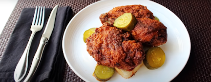 daves hot chicken piece in a plate along with a spoon and knife.