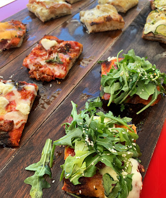 three wooden boards topped with different types of square slices of pizza