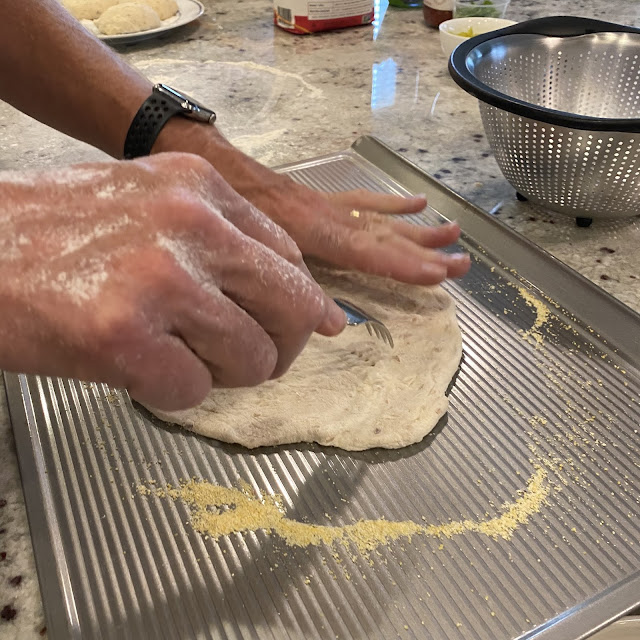 Rolled out pizza dough on a cookie sheet that has been dusted with cornmeal. Prick the dough in about 8 places with a fork.