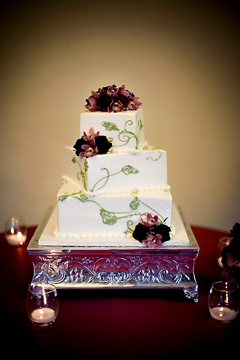Elegant three tier square white wedding cake with green icing leaf patterns 