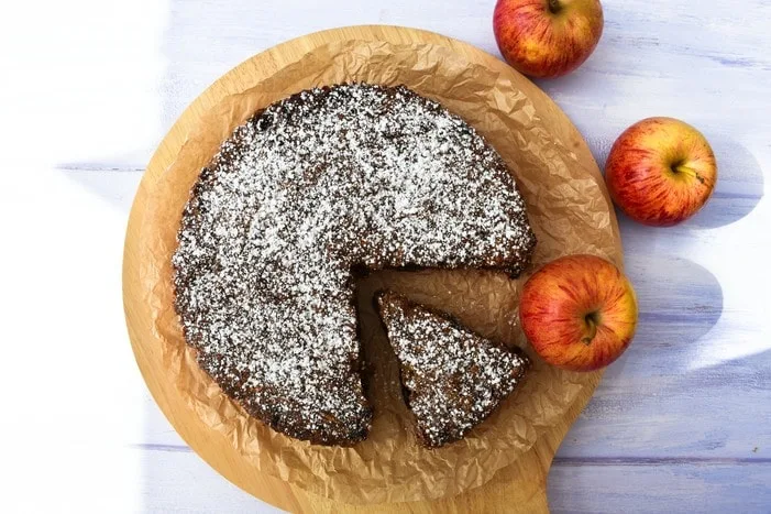 Vegan Red Apple & Treacle Fruit Cake on board drizzled with icing sugar, cut into slices