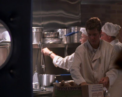 Pacey in a cook's outfit working in a kitchen