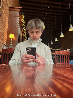 Marshall looking at his phone at the restaurant