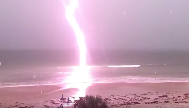 A powerful lighting bolts near the shore.