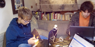 Teenage children sat at table with lap tops open in front of them