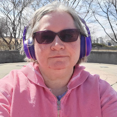 woman in pink outdoors. sunglasses. tree.