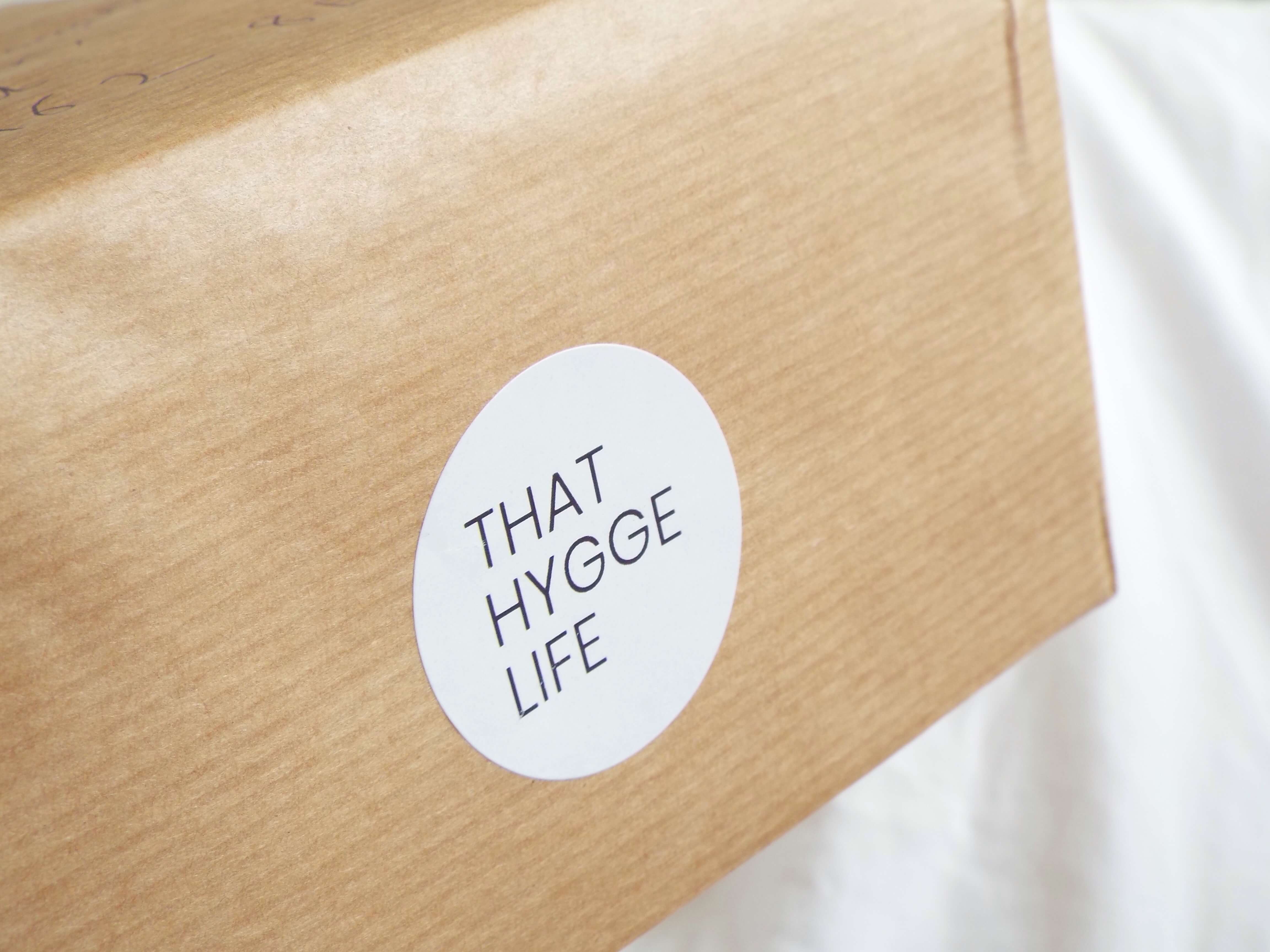 That Hygge Life white circle sticker on brown paper wrapping paper delivery box.