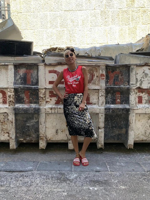 woman posing in sequined skirt in front of dumpster