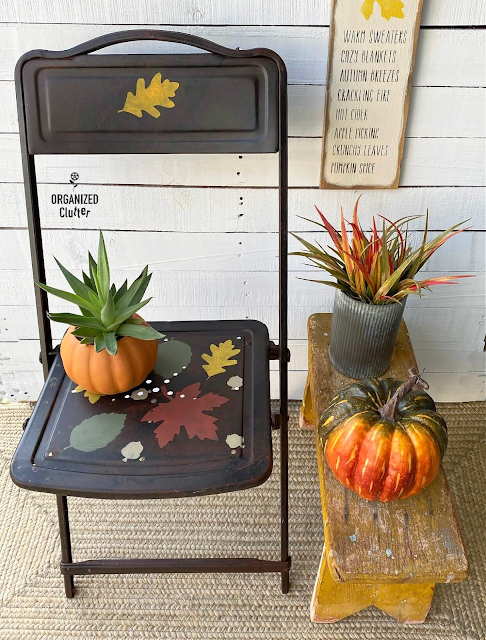 Photo of a rusty folding chair stenciled with fall leaves.