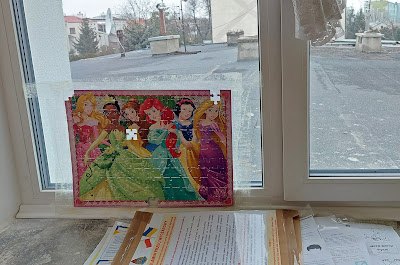 Mostly finished Disney princess puzzle taped to a window