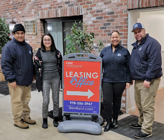 The team at Kent Apartments standing next to sign