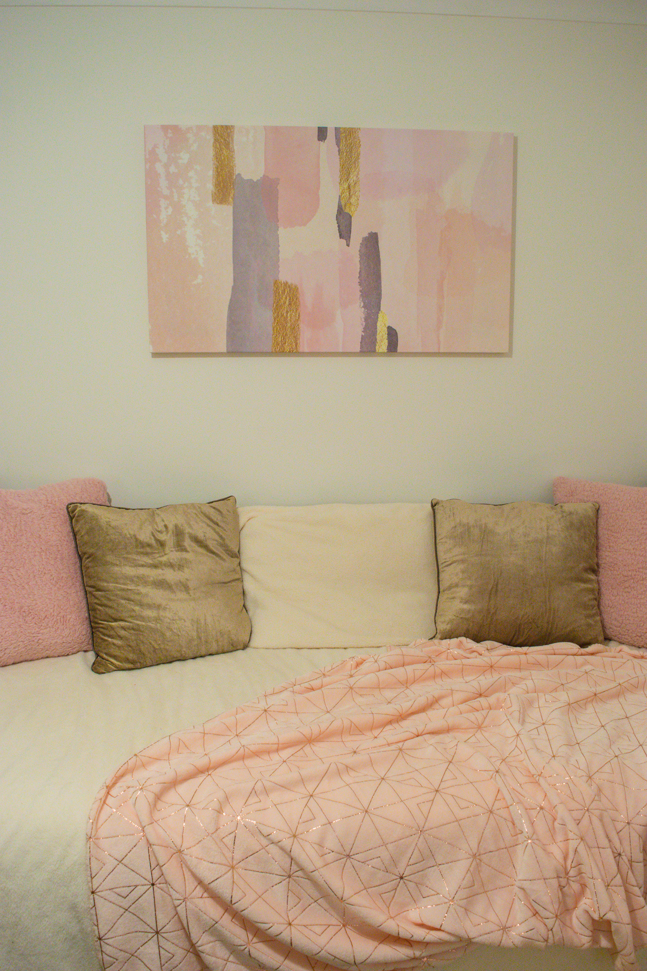 Pink and gold printed canvas above a black framed bed.