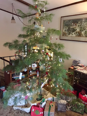 a "Charlie Brown tree" snuggled by presents