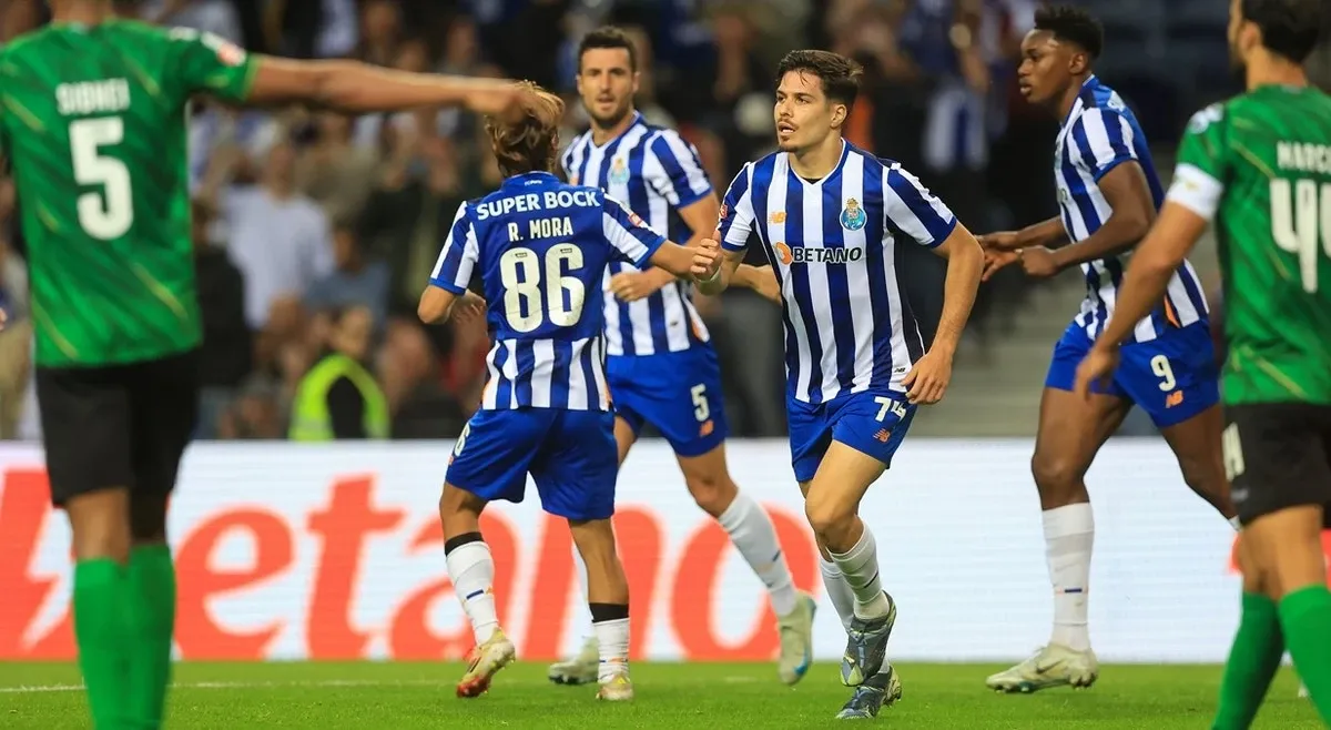 Jogadores do FC Porto comemorando um gol durante uma partida contra Moreirense emocionante, destacando a paixão do futebol em um estádio lotado.