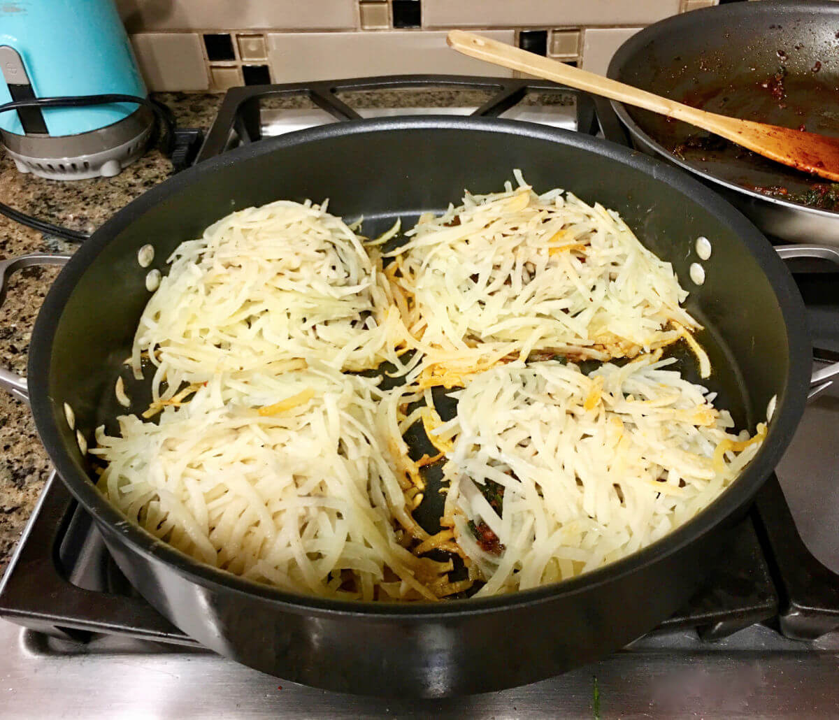 Hash potatoes cooking in a skillet.