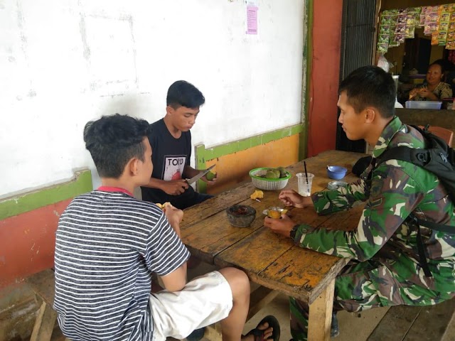 Anggota satgas TMMD jombs sambil makan mangga bersama pemuda desa