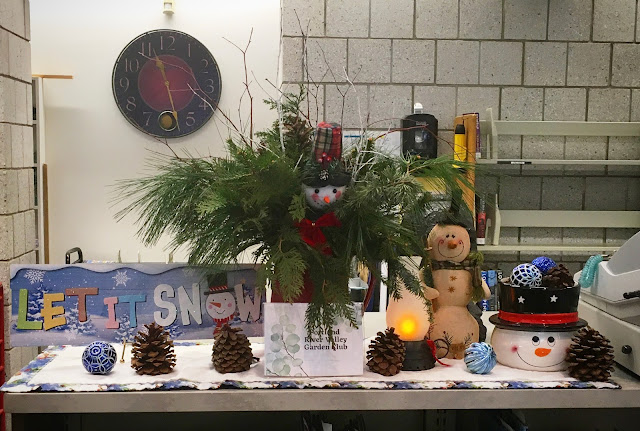 An evergreen display accented with snowmen, pinecones and a "let it snow" sign.