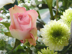 A photo showing a pink rose amongst a bouquet of flowers