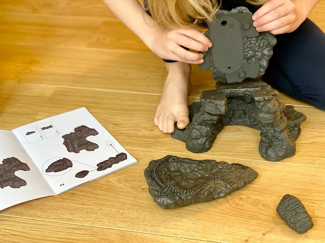 The plastic pieces of the Schleich Dino cave being clicked together by a girl