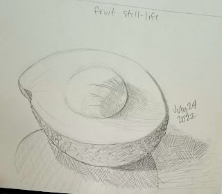 A pencil drawing in a sketchbook of half of an avocado, with the pit still attached.